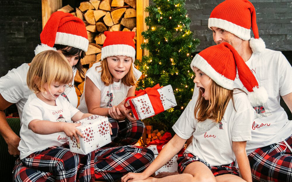 Family opening presents in front of the Christmas tree, wearing Bear Family Christmas Pyjamas